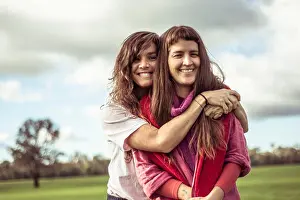 Generation X Prints: two female friends hug and laugh outdoors on green farm land