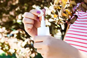 Sneeze Prints: female hand holding a bottle nasal spray in the park