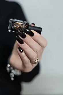 Ring Prints: Female hand with long nails and black manicure holds a bottle of nail polish