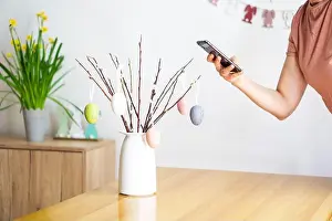 Phone Call Prints: Female hand making photo with smartphone from bouquet with willow branches and colorful Easter eggs