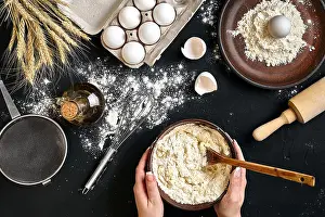 Rising Prints: Female hands making/ mixing dough in brown bowl on black table