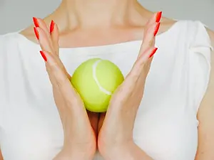 Manicure Prints: Female hands with red manicured nails holds a green tennis ball