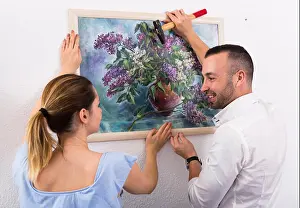 Hammer Prints: Female and her husband are hanging picture together at home