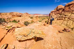 Warm Tone Prints: Female photographer with pack photographing colorful sandstone formations