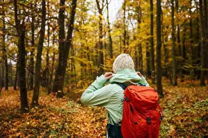 Hood Prints: Female tourist in sports clothing with backpack hiking in autumn forest