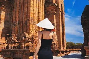 Praying Prints: A female tourist wearing a traditional Non La hat in Vietnam. Towers By Nagar Cham