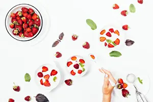 Sundae Prints: Female's hand holding spoon over a bowl of strawberry ice cream among red berries