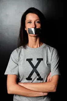 35 39 Years Prints: Femme brune en studio avec un tee-shirt avec un X et du scotch sur la bouche