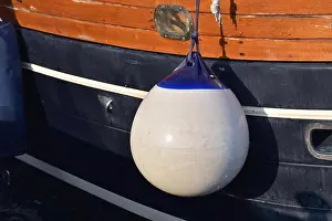 A Fender (boating) hanging on the board to protect the side of the sailing vessel from the damage. Italy