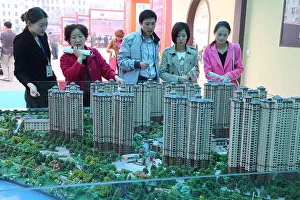 Investors Prints: FILE--Chinese homebuyers look at housing models of a residential apartment project at a real estate fair in Xuchang