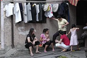--FILE--Female Chinese migrant workers chat and take care of their children outside their rented houses in ChangAn town, Dongguan city, south Chinas G