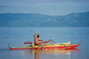 Sea Water Prints: Filipino fisherman waving as he prepares to take his outrigger canoe out to fish in the Visayan Sea off Moalboal