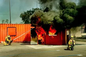 Illuminate Prints: Firemen spray water on a burning model living room in a fire department structural firefighting demonstration in Costa