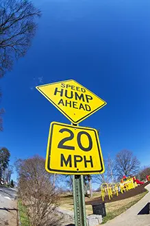 Street Sign Prints: fisheye image of speed hump ahead sign with playground