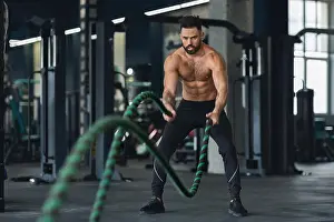 Tiredness Prints: Fitness man working out with battle ropes at gym