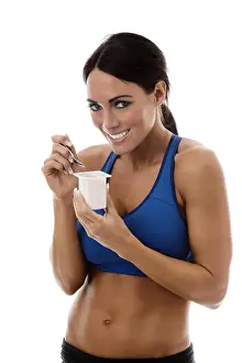 fitness woman wearing sports bra eating yogurt