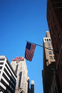 Floors Prints: US flag against blue sky New Yorker Hotel in background