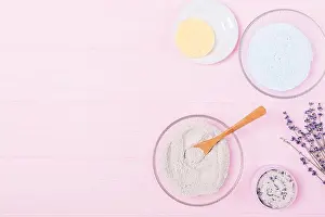 Cleansing Prints: Flat lay cosmetic clay powder in bowl next to lavender flowers on wooden pink table with free space