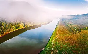 Flight through majestic foggy river and lush green forest at sunrise time. Landscape photography. Dnister, Ukraine, Europe