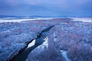 Flight through majestic river, frozen forest and frosty winter fields at sunrise time. Landscape photography