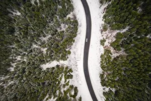 Flight over the winter mountains with road serpentine and snowy forest. Top down view. Landscape photography