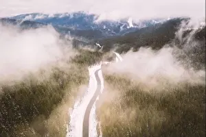 Flight over the winter mountains with road serpentine and snowy forest. Top down view. Landscape photography