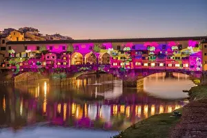 Florence, Italy at the Ponte Vecchio Bridge crossing the Arno River at twilight with holiday illumination