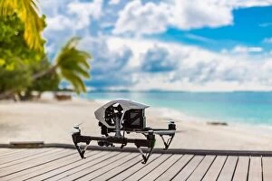 Images Dated 17th December 2015: Flying drone with mounted camera at the beach. Palm trees and blue lagoon