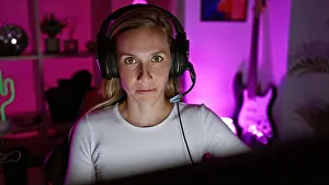 Gamer Prints: Focused blonde woman wearing headphones in a vibrant pink-lit gaming room at night