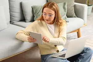 Concentrating Prints: Focused woman using digital tablet and laptop for remote work or online learning at home