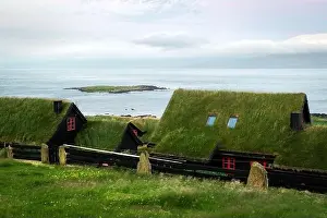 Foggy morning view of a house with typical turf-top grass roof and blue cloudy sky in the Velbastadur village on Streymoy island, Faroe islands