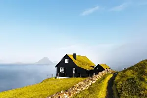 Foggy morning view of a house with typical turf-top grass roof in the Velbastadur village on Streymoy island, Faroe islands, Denmark