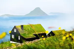 Foggy morning view of a house with typical turf-top grass roof in the Velbastadur village on Streymoy island, Faroe islands, Denmark. Landscape photog