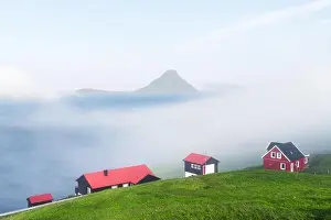 Foggy morning view of a houses with red roof in the Velbastadur village on Streymoy island, Faroe islands, Denmark. Landscape photography