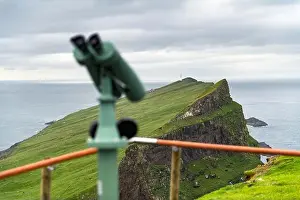 Foggy view of old lighthouse from viewpoint with tourist binoculars on the Mykines island, Faroe islands, Denmark. Landscape photography