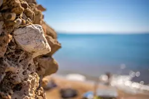 in the foreground is a stone wall and in the background is the blue sea in beautiful weather