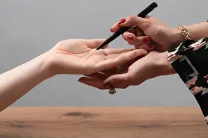 Telling Prints: Fortune teller reading lines on woman's palm at wooden table, closeup. Chiromancy
