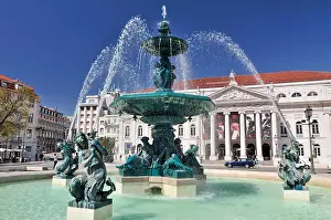 Rossio Prints: Fountain and historic building at central square with blue sky on a sunny day