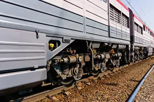 Springs Prints: fragment of a sunlit modern locomotive on a track with truck frames extending into perspective