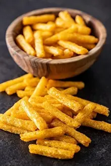 French fries. Salted snack. Potato chips on black table