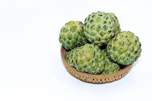 Pulp Prints: Fresh green Custard apples kept on a wooden basket with white background