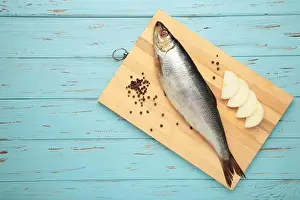 White Sea Prints: Fresh herring fish on cutting board on blue wooden background. Top view