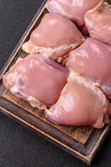 Freshness Prints: Fresh raw chicken thigh fillets with salt, spices and herbs on a dark concrete background
