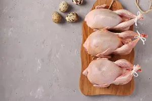 Thanksgiving Prints: Fresh raw organic quails on wooden board and quail eggs on a gray background, Copy space