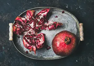 Pomegranate Prints: Fresh ripe pomegranate broken in metal tray over plywood background