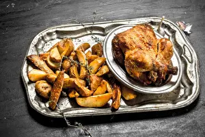 Fried chicken with potatoes on a tray. On the black chalkboard