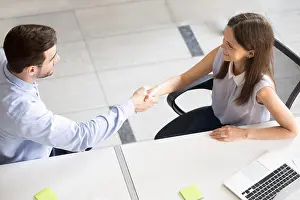 Woman Work Prints: Friendly smiling employee shaking hand with young woman