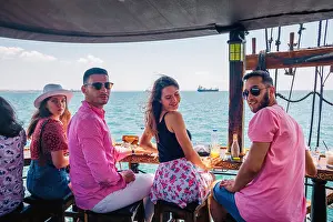 Sails Prints: Friends drink coffee on a boat while they chill and enjoy the amazing view