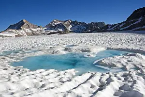 Sierra Nevada Prints: frozen lake in the high Sierra starting to melt out in July with blue water in the snow and mountains on the horizon
