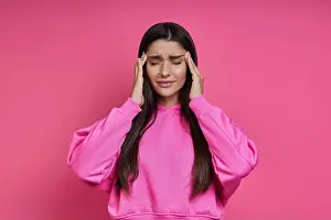 Eyes Closed Prints: Frustrated woman touching head with hands and keeping eyes closed against pink background